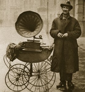A street hawker entertains with a gramophone, transported in a pram